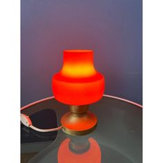 an orange lamp sitting on top of a glass table next to a phone charger