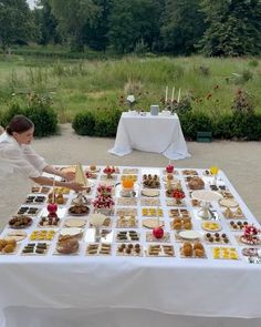 a woman is setting up a table with desserts on it