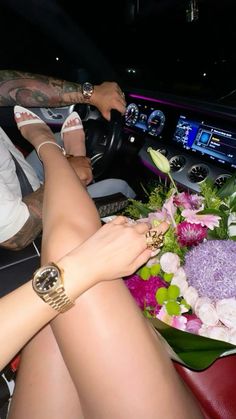 two people sitting in the drivers seat of a car with flowers on the dash board