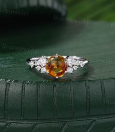 an orange and white diamond ring sitting on top of a green surface