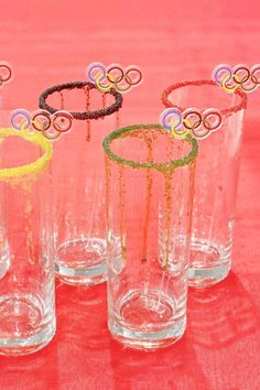 four glasses with different designs on them sitting on a red tablecloth covered table cloth