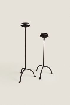 two black candlesticks sitting next to each other on top of a white surface