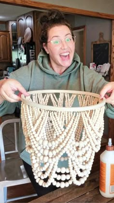 a man holding up a basket made out of beads and wood bead balls in front of his face