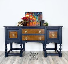 a blue dresser with two drawers and a painting on the wall