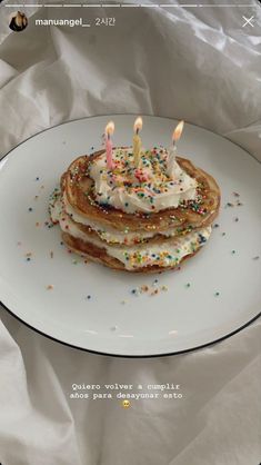 a stack of pancakes topped with white frosting and sprinkles on a plate