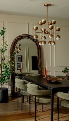 a dining room table with chairs and a mirror on the wall next to potted plants