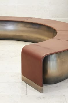 a curved bench sitting on top of a white tiled floor