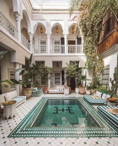 an indoor swimming pool surrounded by potted plants and greenery in the middle of a courtyard