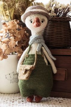 a crocheted snowman doll sitting next to a basket with flowers in it