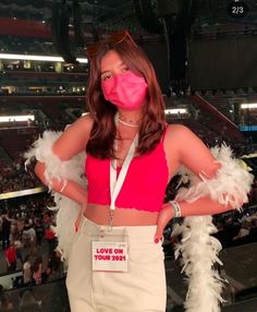 a woman in pink shirt and white feather skirt standing next to an audience with her mouth covered