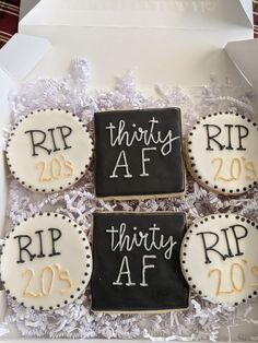 three decorated cookies in a box with white frosting and black lettering on them that say thirty af, thirty af