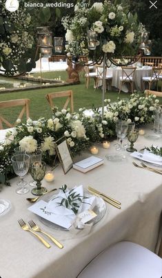 the table is set with white flowers and greenery