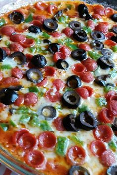 a pizza with pepperoni, olives and green peppers on it sitting on a table