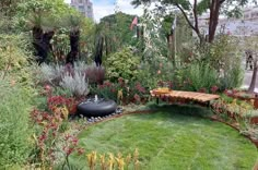 a circular garden with lots of plants and flowers around it, along with a bench in the middle