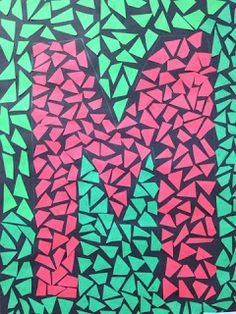 the letter m is made up of small pieces of colored paper and black, green, pink, and blue triangles