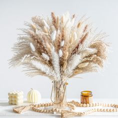 a vase filled with lots of dry grass next to some beads and other items on a table