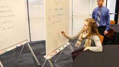 two people standing in front of a whiteboard with writing on it