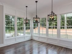 an empty room with three chandeliers hanging from the ceiling and wood flooring