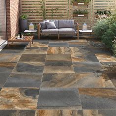 an outdoor living area with couches, tables and plants on the side of it