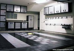 an empty garage with checkered flooring and lots of cabinets on either side of the room