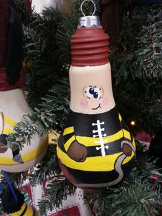 a christmas tree ornament with a football painted on it's bottle and another decoration in the background