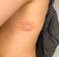 a small sun tattoo on the back of a woman's right arm and shoulder