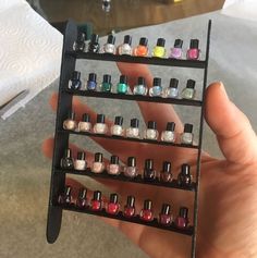 a person holding a rack with many different nail polishes on it's sides