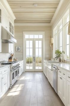 a large kitchen with white cabinets and wood flooring, along with an open door leading to the outside