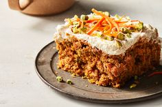 a piece of carrot cake sitting on top of a black plate next to a cup