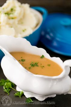 two bowls filled with mashed potatoes and gravy next to each other on a table