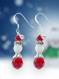 a pair of red and white earrings sitting on top of a snow covered ground