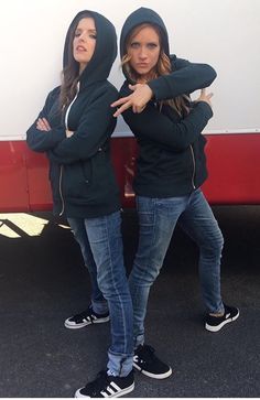 two young women standing in front of a trailer pointing to the side with their arms crossed