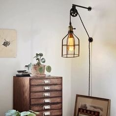 a lamp that is sitting on top of a dresser next to a potted plant