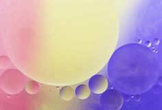 an image of bubbles floating in the air on a rainbow colored background with blue, pink, and yellow hues