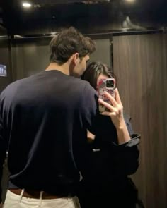 a man and woman taking a selfie in front of a mirror while standing next to each other