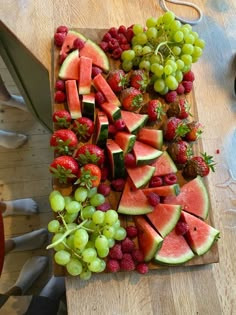 a cutting board topped with watermelon, grapes and strawberries