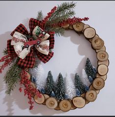 a christmas wreath made out of wood slices and pine trees with a bow on top