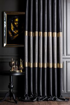 a black and gold curtain hanging in front of a painting