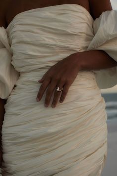 a close up of a person wearing a dress with a diamond ring on it's finger