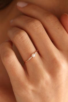 a woman's hand wearing a gold ring with white stones on the middle finger