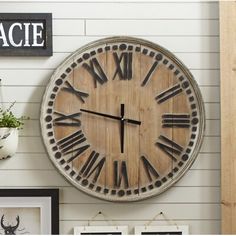 a large clock mounted to the side of a wall next to pictures and framed photos