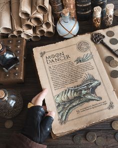 a person holding an open book on top of a table filled with coins and other items