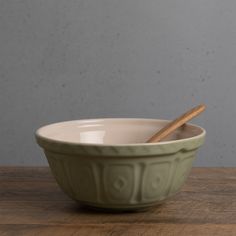 a bowl with a wooden spoon in it sitting on a table next to a wall