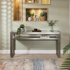 a table with some plants on it in front of two framed pictures and a potted plant