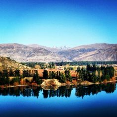 a lake surrounded by mountains with trees in the foreground