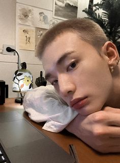 a young man sitting in front of a laptop computer with his hand on his face