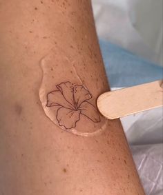 a woman's arm with a flower on it and a wooden spatula in front of her