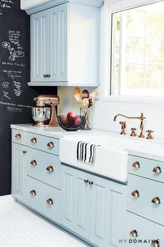 a kitchen with chalkboard on the wall and white cabinets