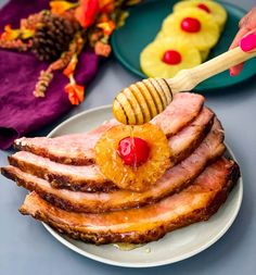 a plate topped with sliced ham and pineapples next to other plates filled with fruit