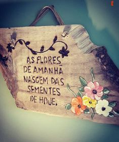 a wooden sign with flowers on it that says as flores de amanha nasgem da sementes de hoje